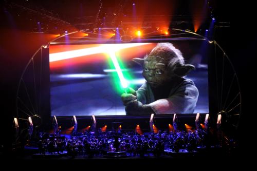Yoda brandishes a light sabre onscreen over the orchestra during one of the musical segments of Star Wars™: In Concert.